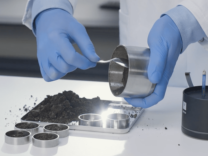 A photograph of a researcher scooping soil sample out of a HYPROP sample ring