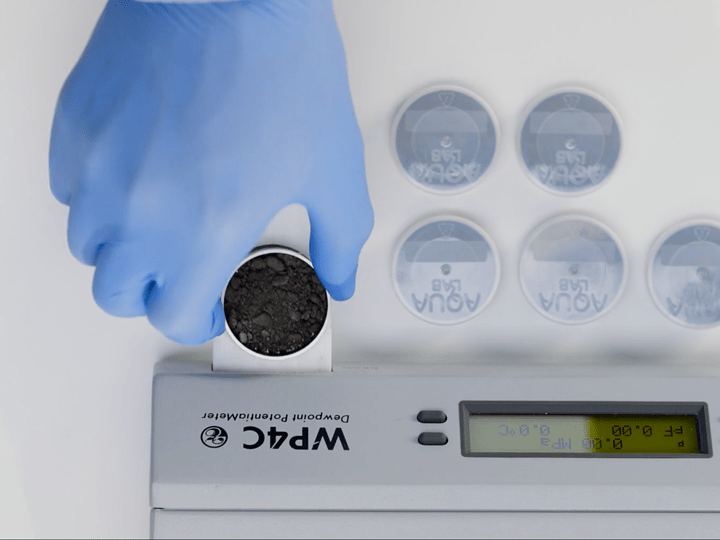 A researcher placing a sample in the drawer of a WP4C dew point hygrometer